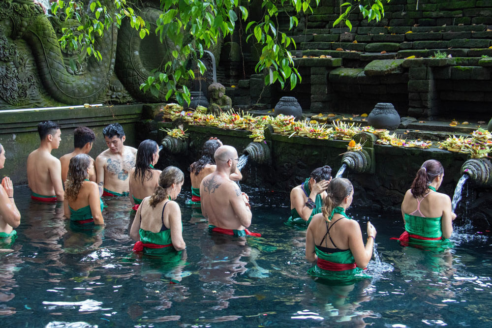 group of people purification in tirtal empul for balinese spiritual experience